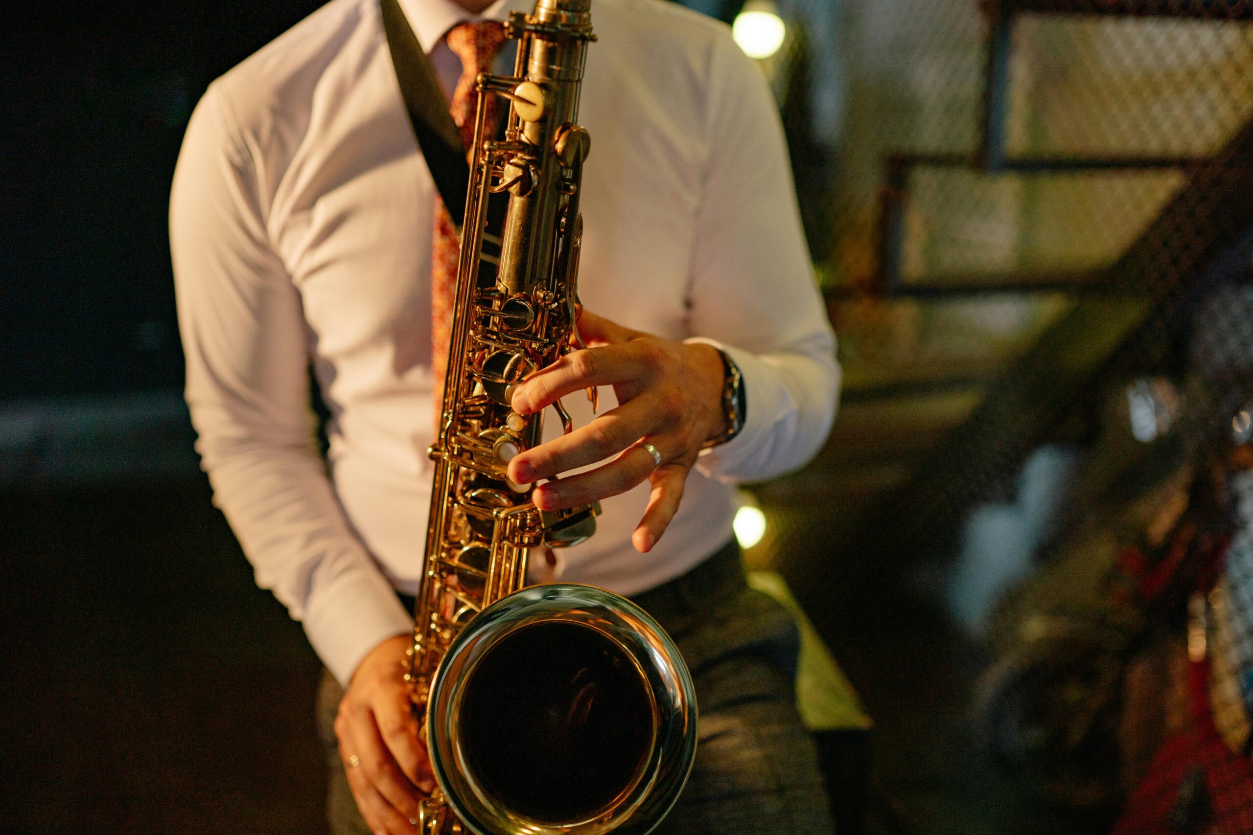 A musician in formal attire plays the saxophone indoors, showcasing musical talent.